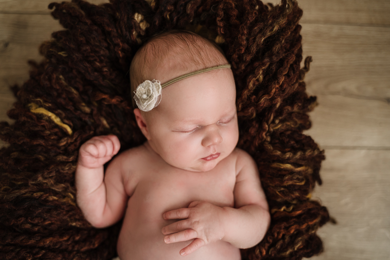 Schlafendes Baby mit Stirnband auf braunem Hintergrund – Babyfotografie in Vallendar und Koblenz