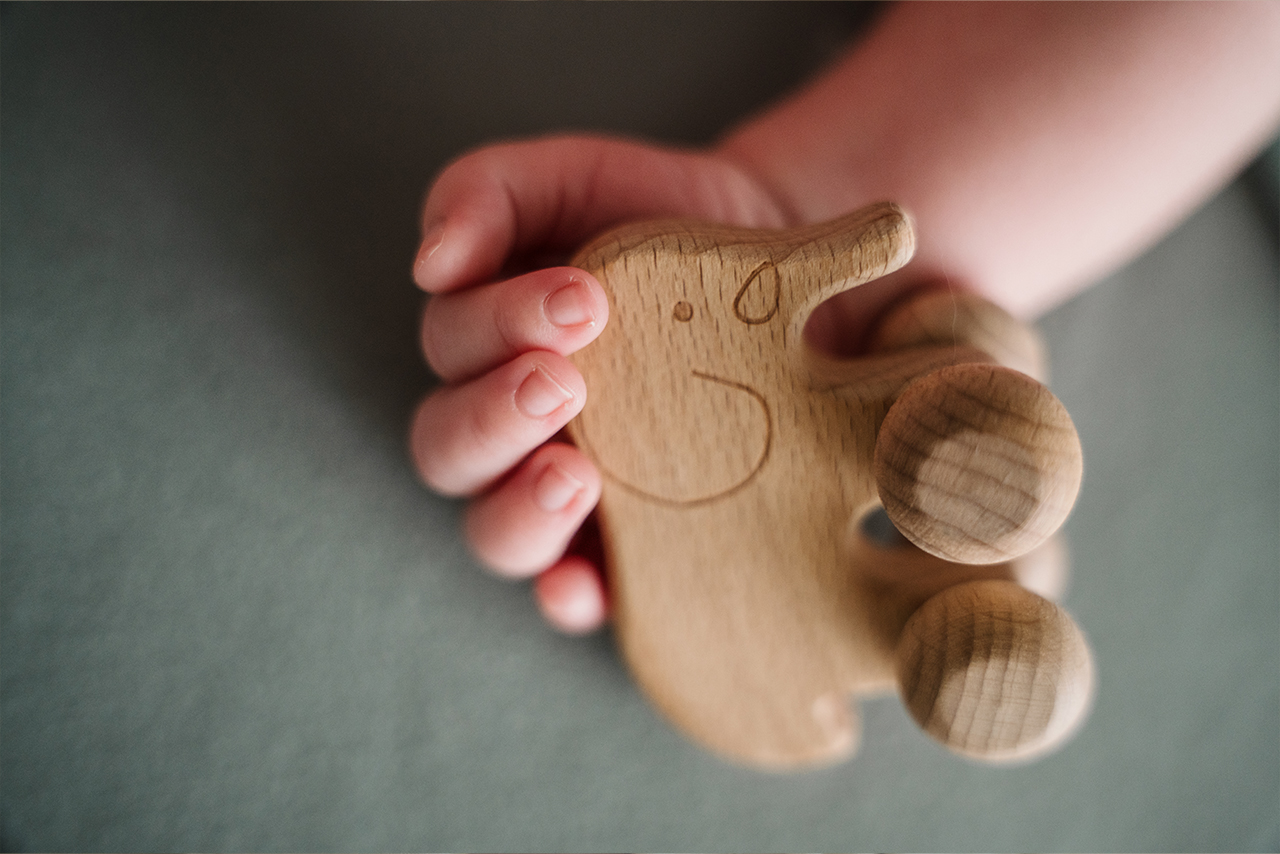 Babyhand hält ein Holzspielzeug – Detailaufnahme aus Vallendar und Koblenz